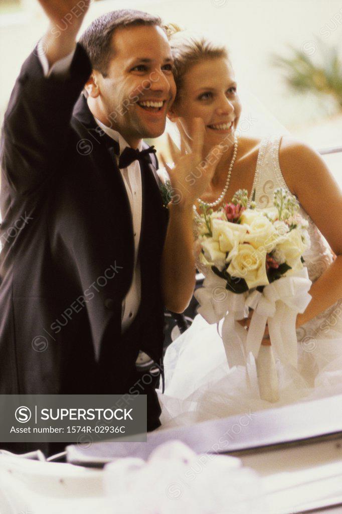 Stock Photo: 1574R-02936C Newlywed couple waving from a convertible car