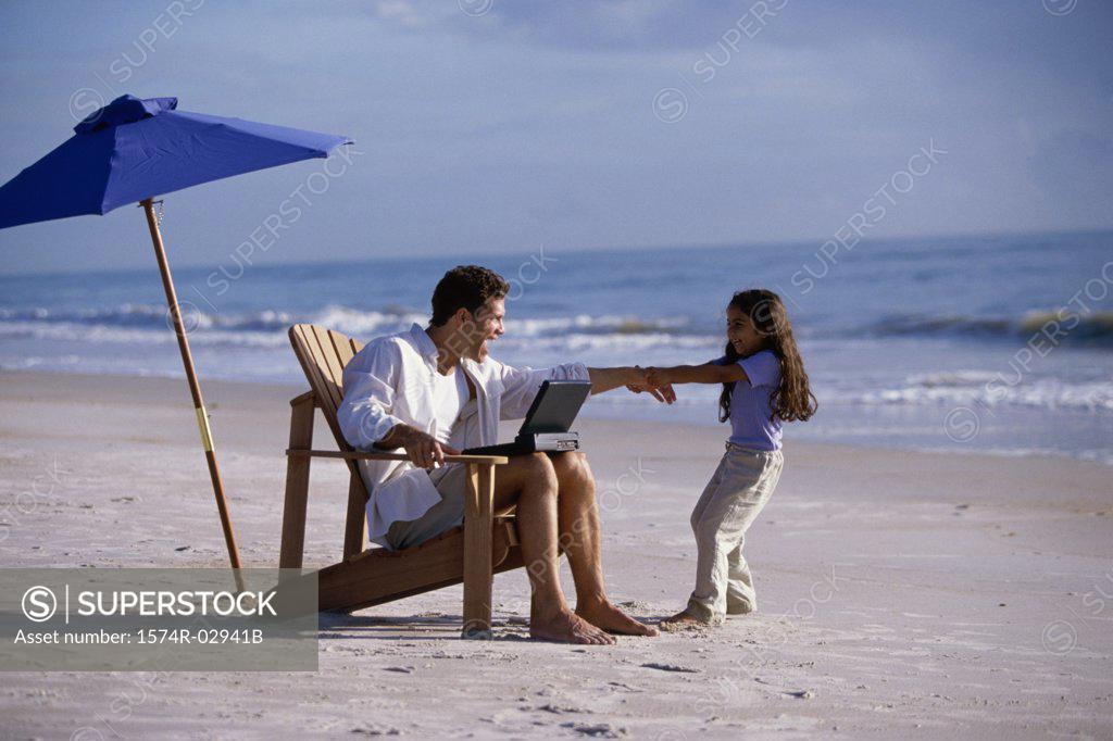 Stock Photo: 1574R-02941B Father working on a laptop with his daughter pulling at his arm