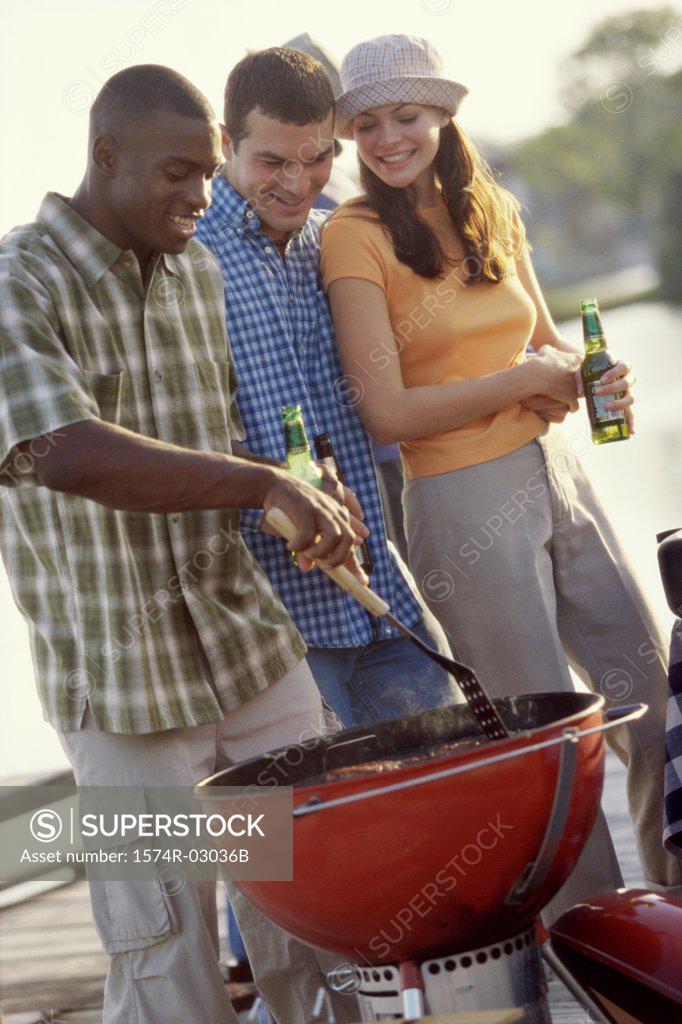 Stock Photo: 1574R-03036B Two young men and a young woman at a barbecue