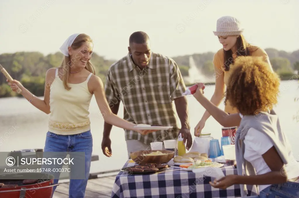 Three young women and a young man at an outdoor picnic together
