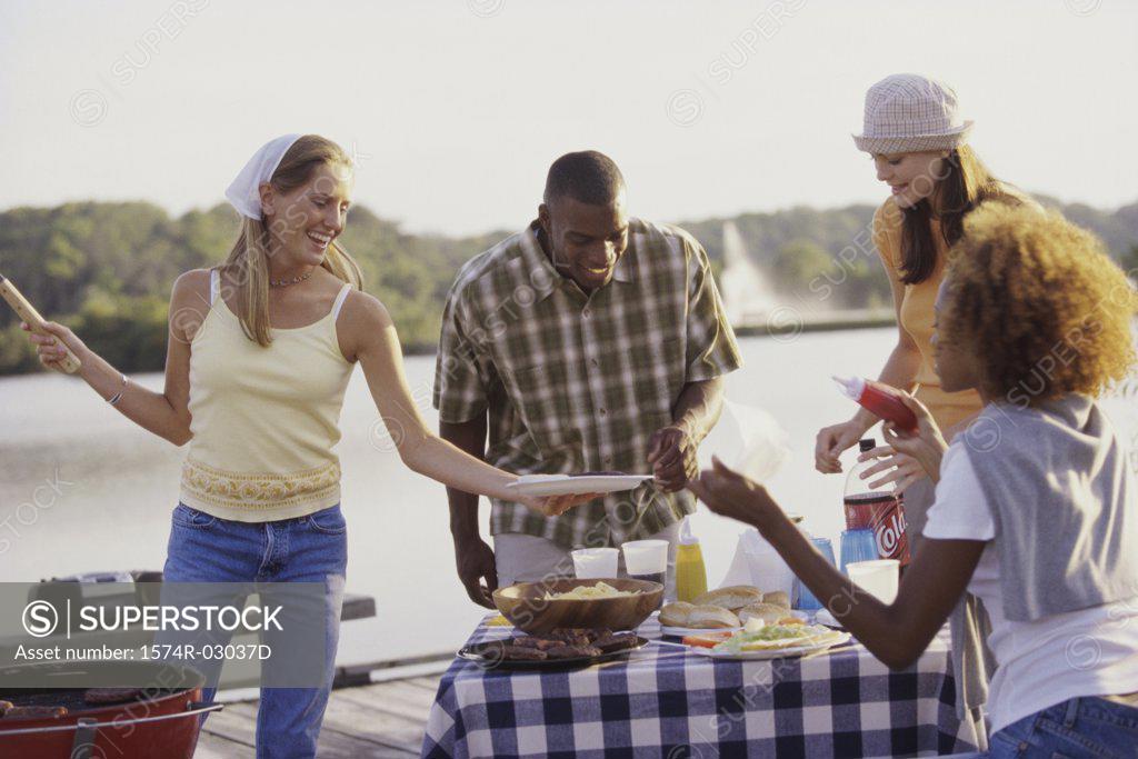 Stock Photo: 1574R-03037D Three young women and a young man at an outdoor picnic together