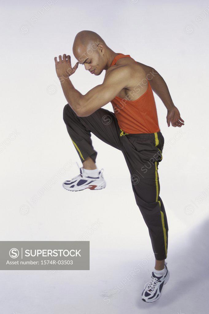 Stock Photo: 1574R-03503 Side profile of young man lifting his leg