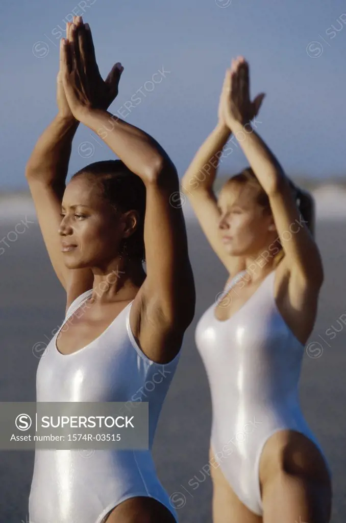 Two young women exercising on the beach