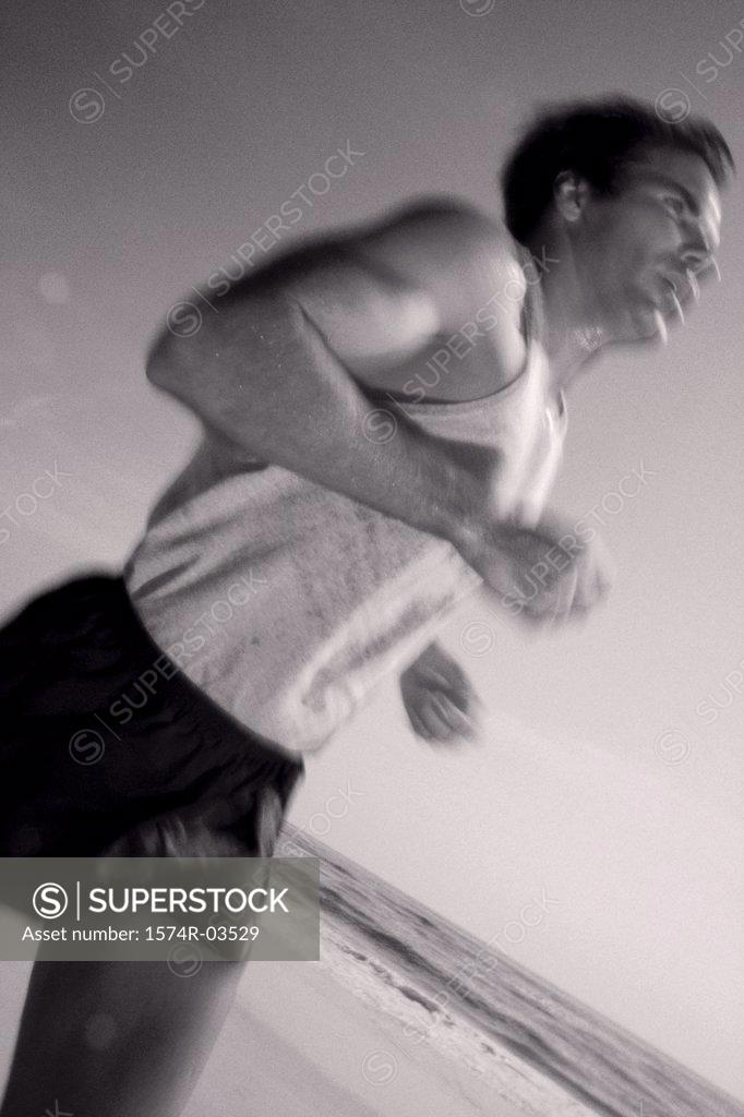 Stock Photo: 1574R-03529 Side profile of a young man jogging on the beach