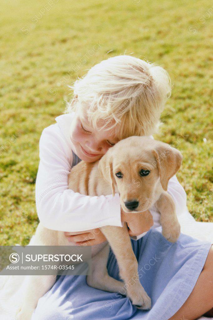 Stock Photo: 1574R-03545 Girl sitting on a lawn holding a puppy