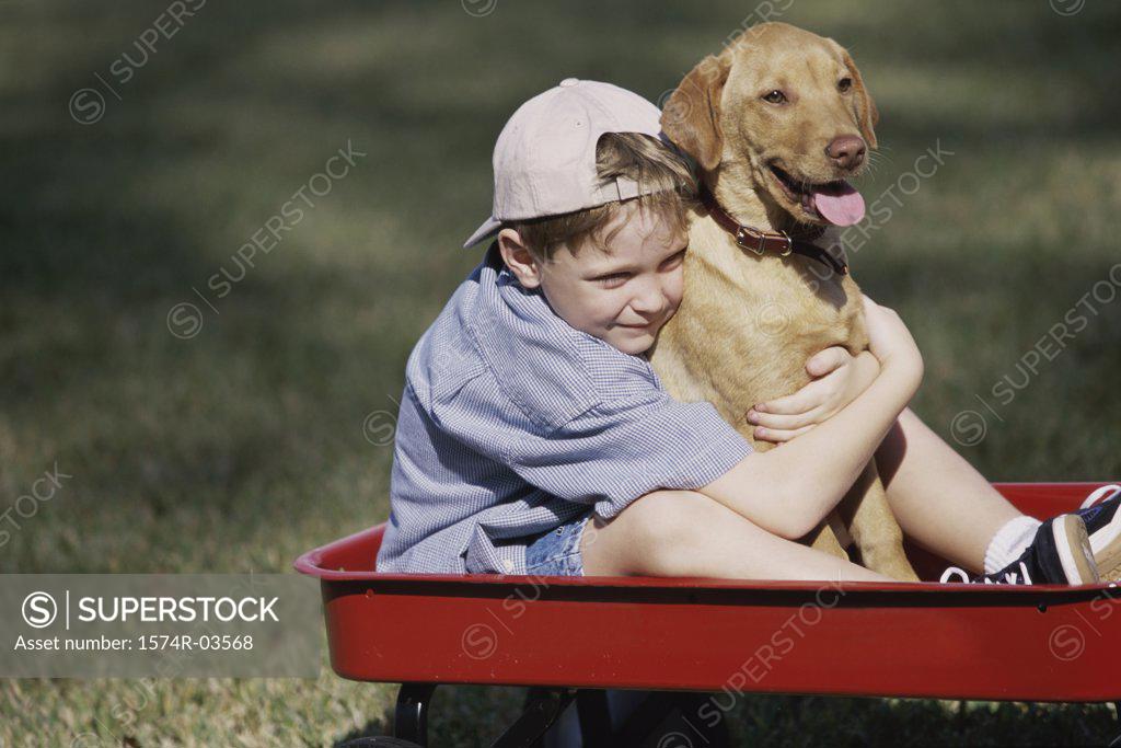 Stock Photo: 1574R-03568 Boy sitting in a toy wagon holding his dog