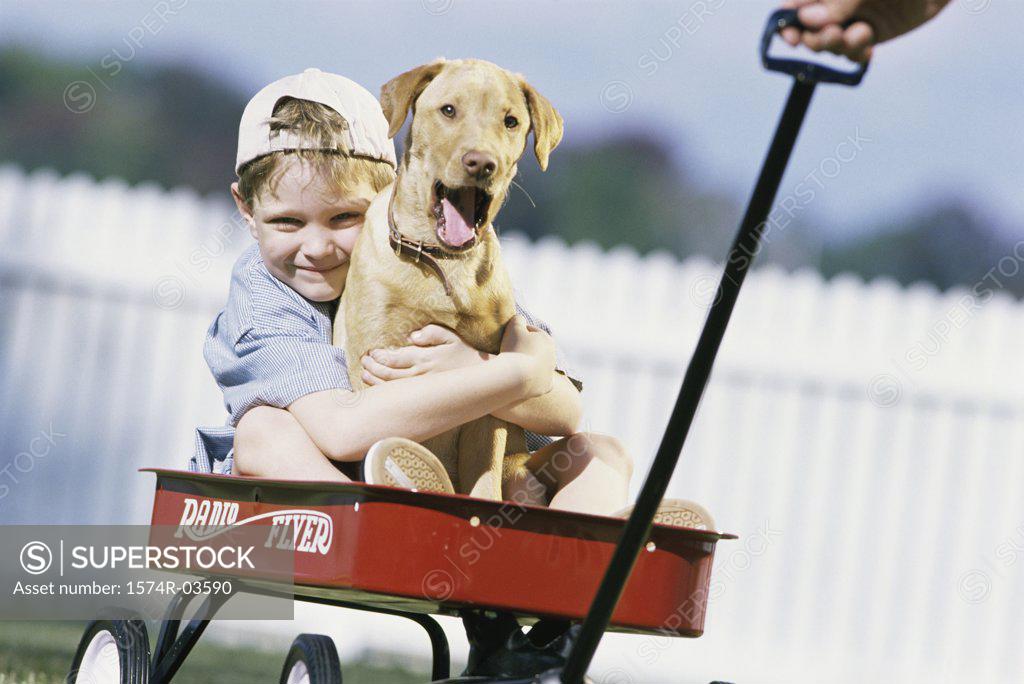 Stock Photo: 1574R-03590 Boy sitting in a toy wagon holding his dog