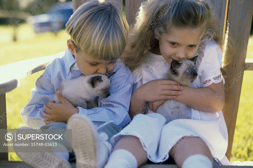 Stock Photo: 1574R-03613 Boy and a girl sitting with Siamese kittens