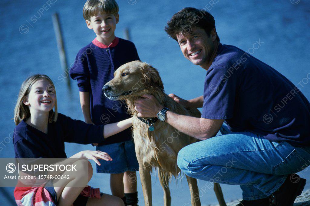 Stock Photo: 1574R-03642 Father and his son and daughter playing with their dog
