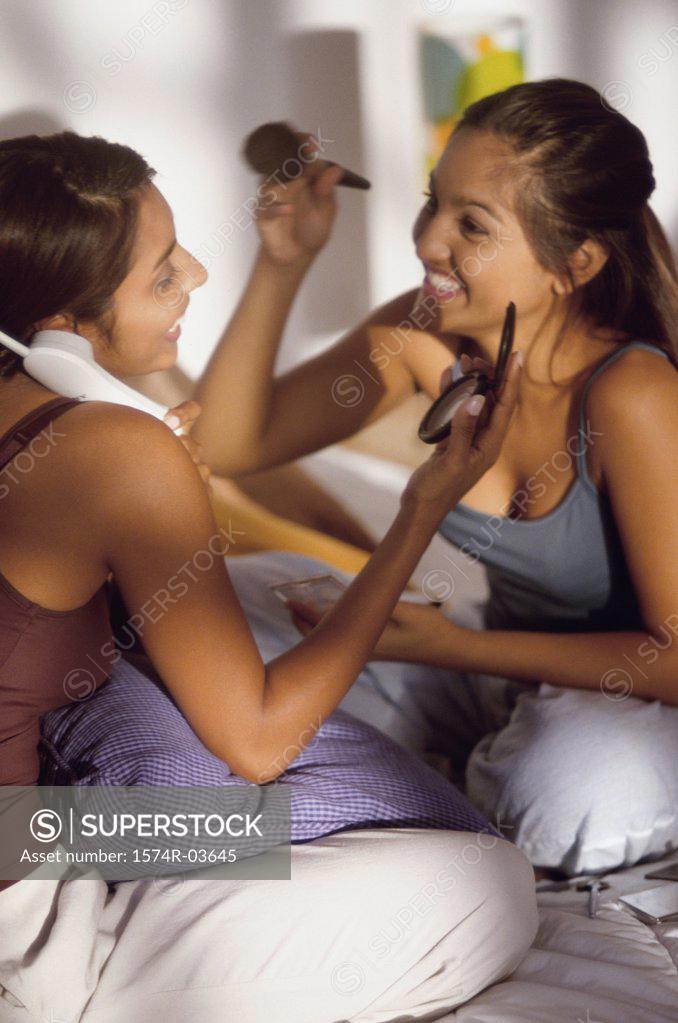 Stock Photo: 1574R-03645 Two teenage girls playing and talking on the telephone