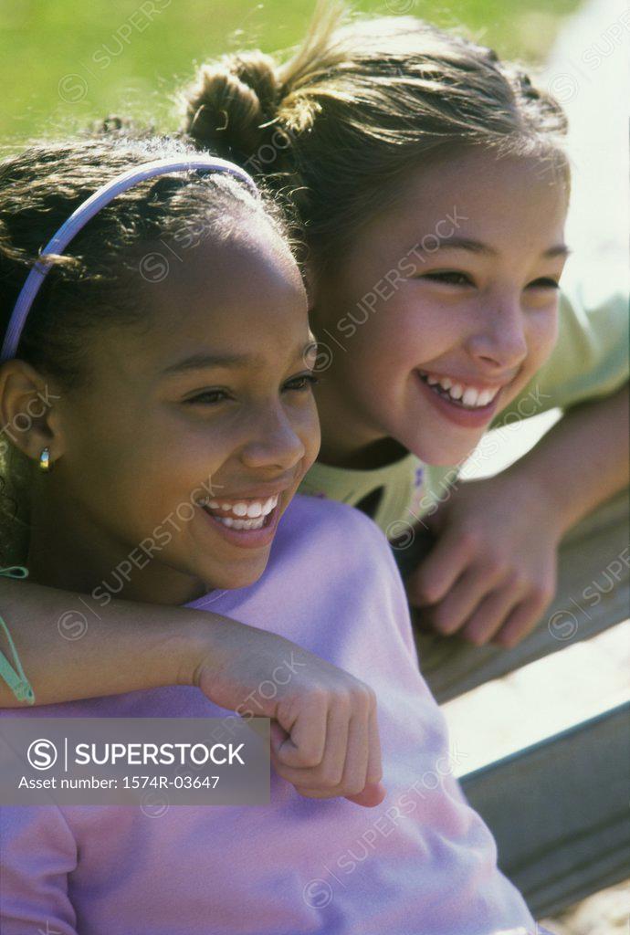 Stock Photo: 1574R-03647 Two girls sitting on a bench smiling