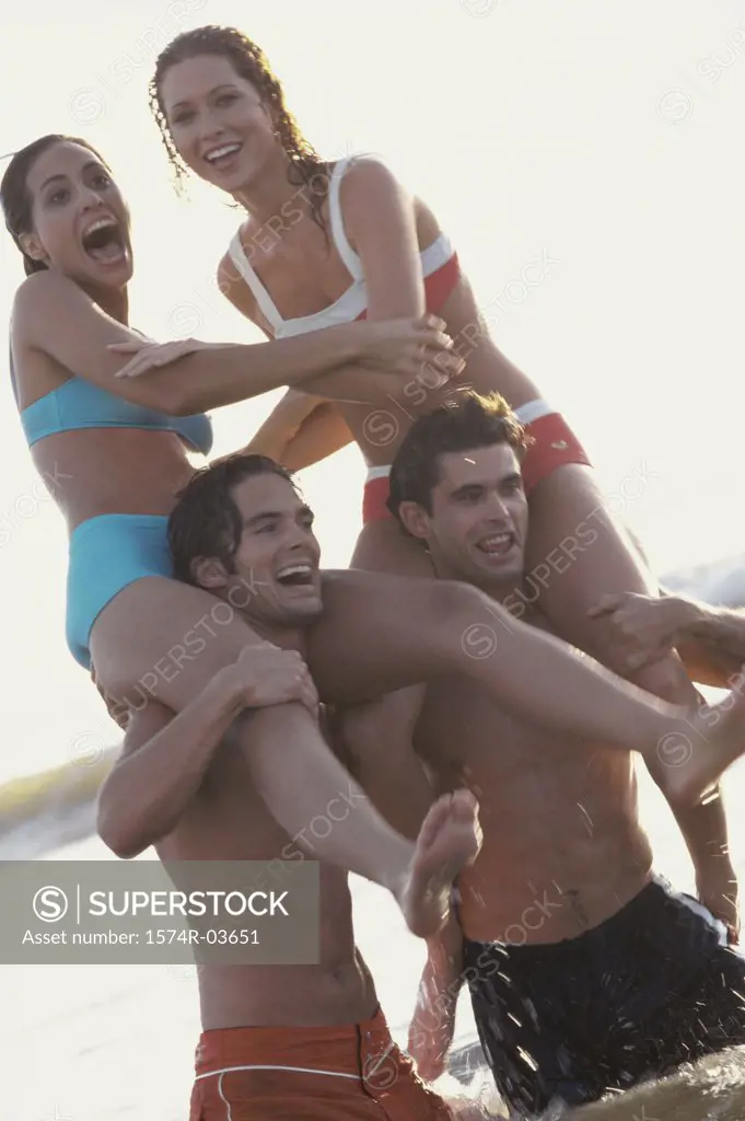 Young men carrying women on shoulders on the beach