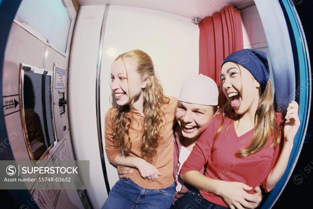 Stock Photo: 1574R-03652 Two teenage girls and a teenage boy sitting in a photo booth