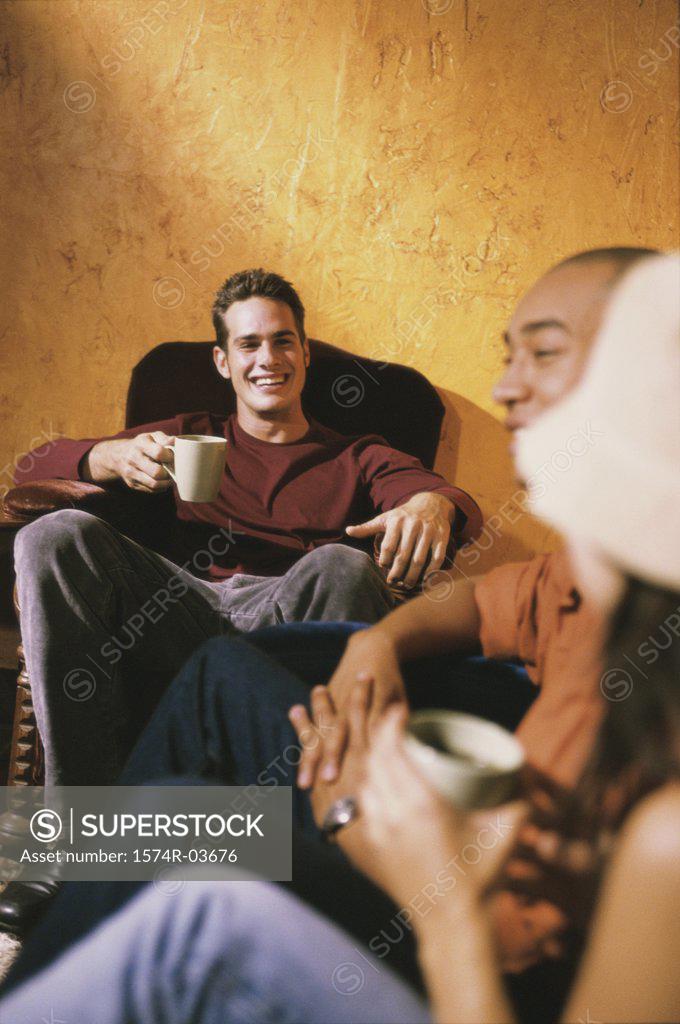 Stock Photo: 1574R-03676 Two young men and a young woman sitting in a cafe drinking coffee