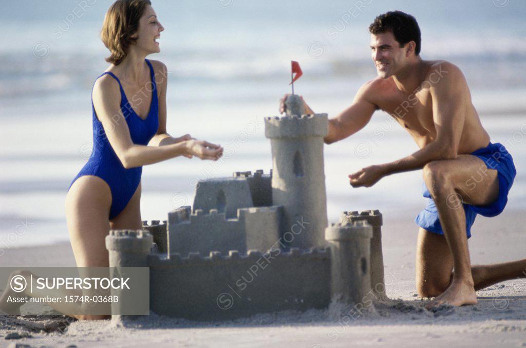 Stock Photo: 1574R-0368B Young couple building a sandcastle on the beach