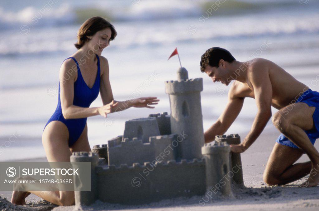 Stock Photo: 1574R-0368D Young couple building a sandcastle on the beach