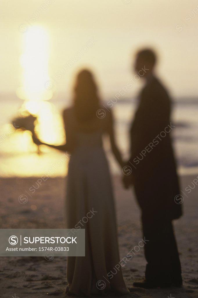 Stock Photo: 1574R-03833 Newlywed couple standing on the beach