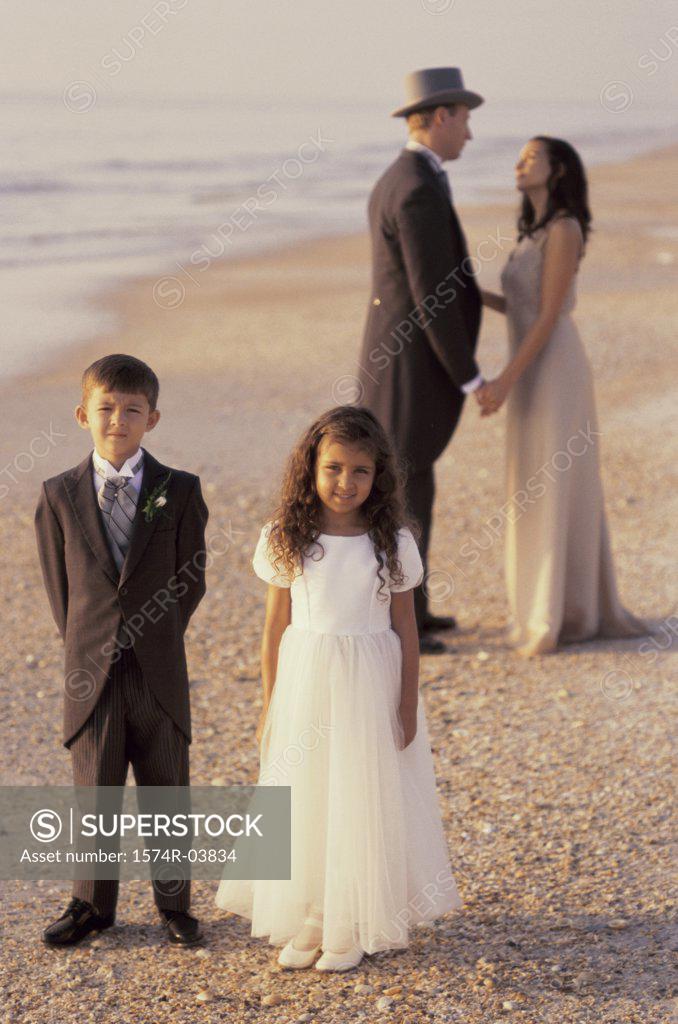 Stock Photo: 1574R-03834 Newlywed couple standing on the beach with a flower girl and a ring bearer