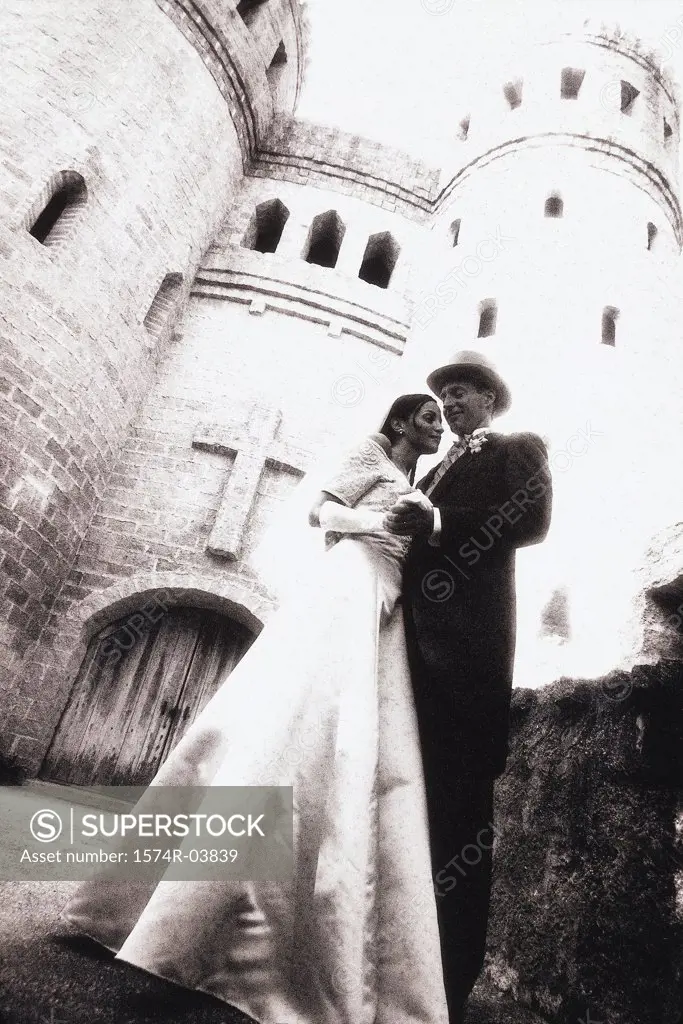 Low angle view of a newlywed couple standing outside of a castle