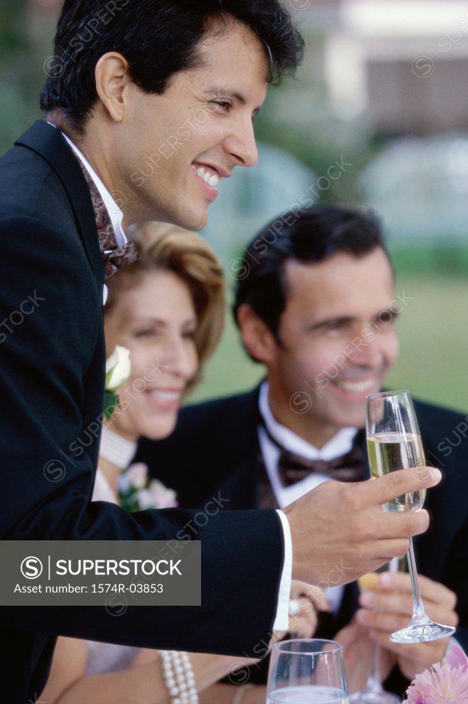 Stock Photo: 1574R-03853 Newlywed young man toasting champagne with mid adult couple