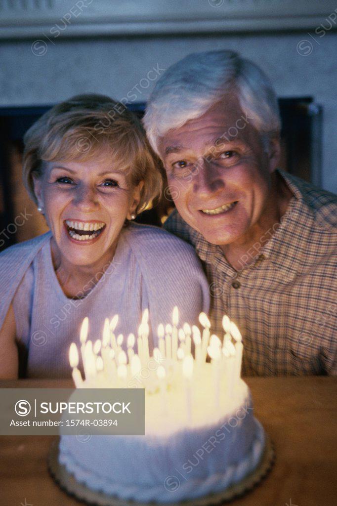 Stock Photo: 1574R-03894 Senior couple blowing out candles on a cake