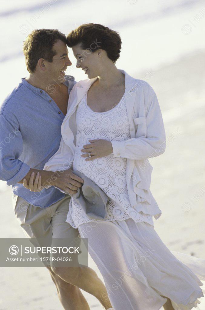 Stock Photo: 1574R-04026 Husband walking on the beach with his pregnant wife