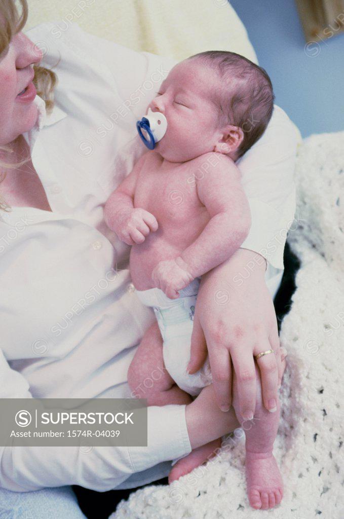 Stock Photo: 1574R-04039 Close-up of a baby boy sucking on a pacifier sleeping in his mother's arms