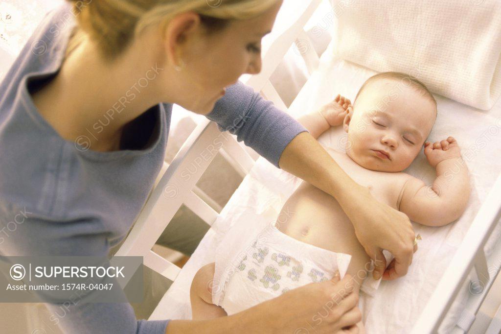 Stock Photo: 1574R-04047 High angle view of a mother changing diaper of sleeping baby boy