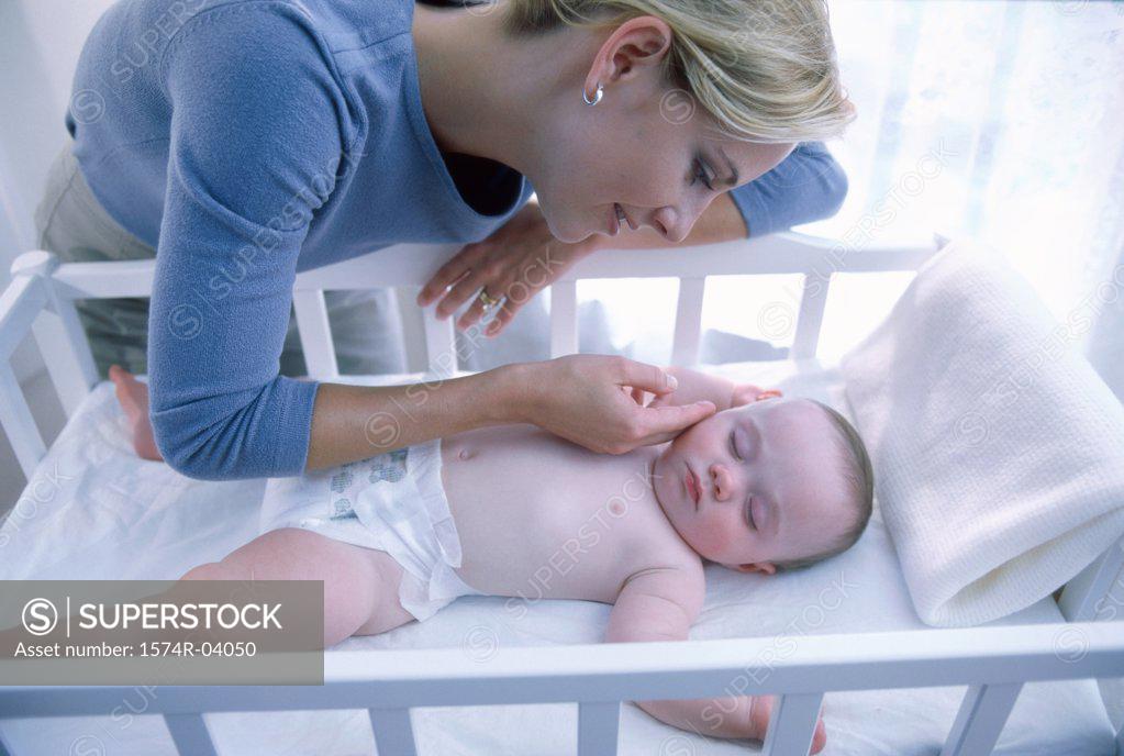 Stock Photo: 1574R-04050 Mother looking at her baby boy in a crib