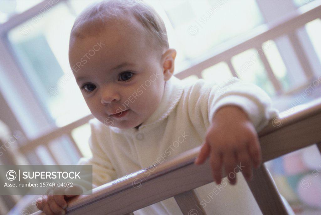 Stock Photo: 1574R-04072 Close-up of a baby boy holding the railing of a crib
