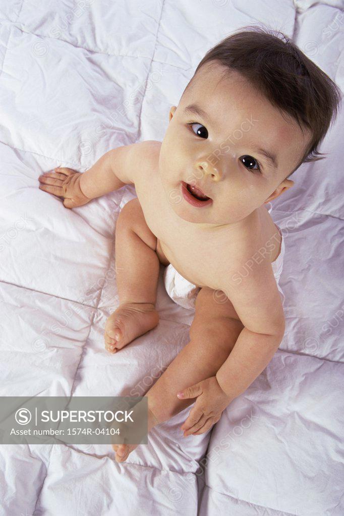 Stock Photo: 1574R-04104 High angle view of a baby boy sitting on a bed
