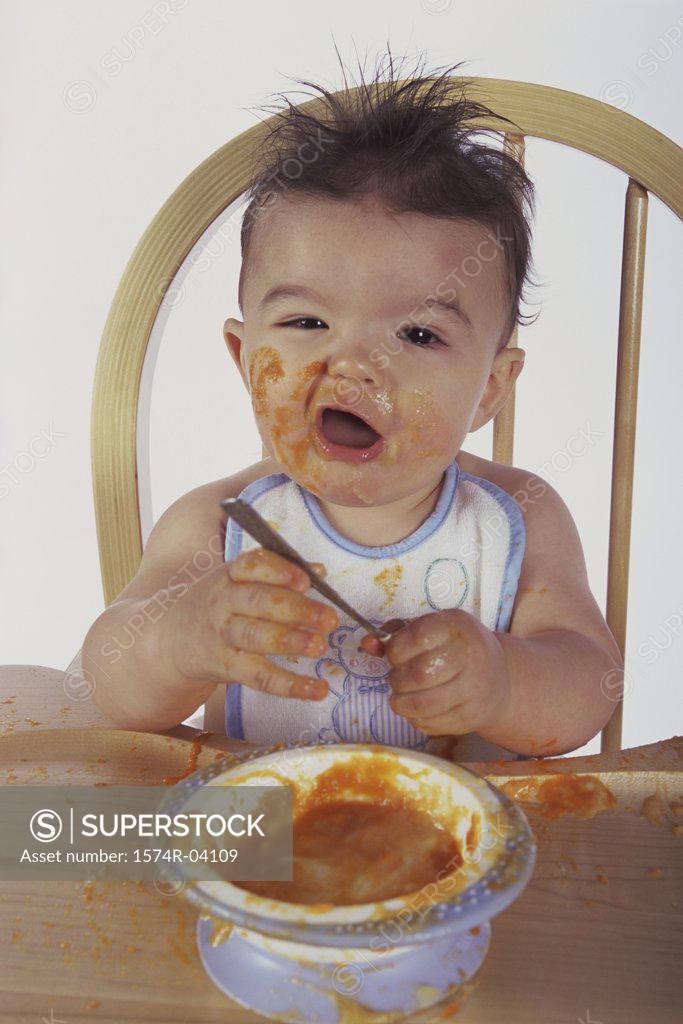 Stock Photo: 1574R-04109 Portrait of a baby boy sitting on a chair eating
