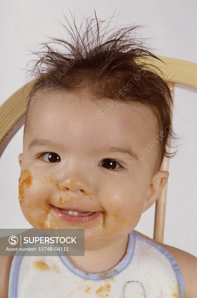 Portrait of a baby boy smiling with food on his face
