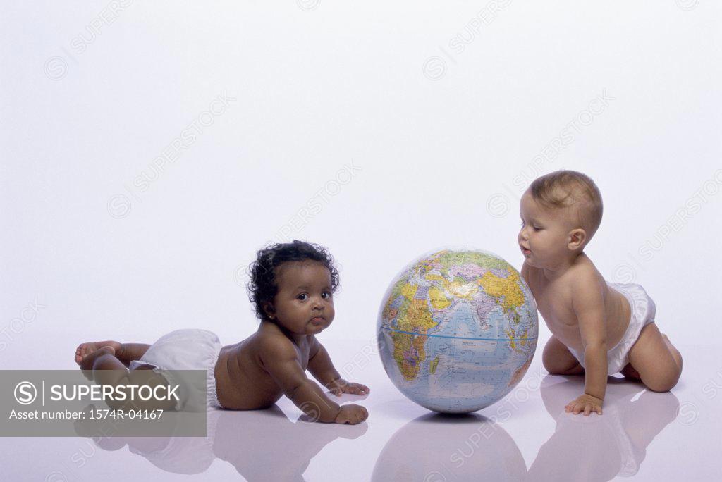 Stock Photo: 1574R-04167 Baby boy and a baby girl playing with a globe