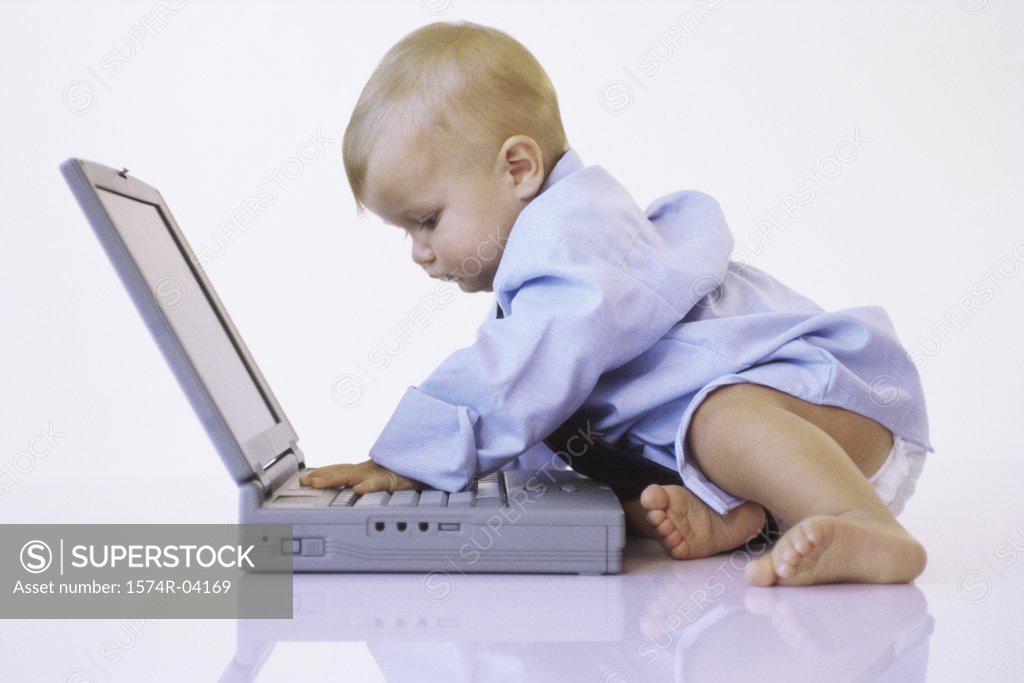 Stock Photo: 1574R-04169 Side profile of a baby boy touching a laptop