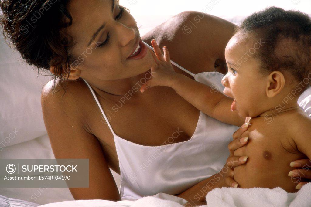 Stock Photo: 1574R-04190 Mother lying on a bed with her baby girl