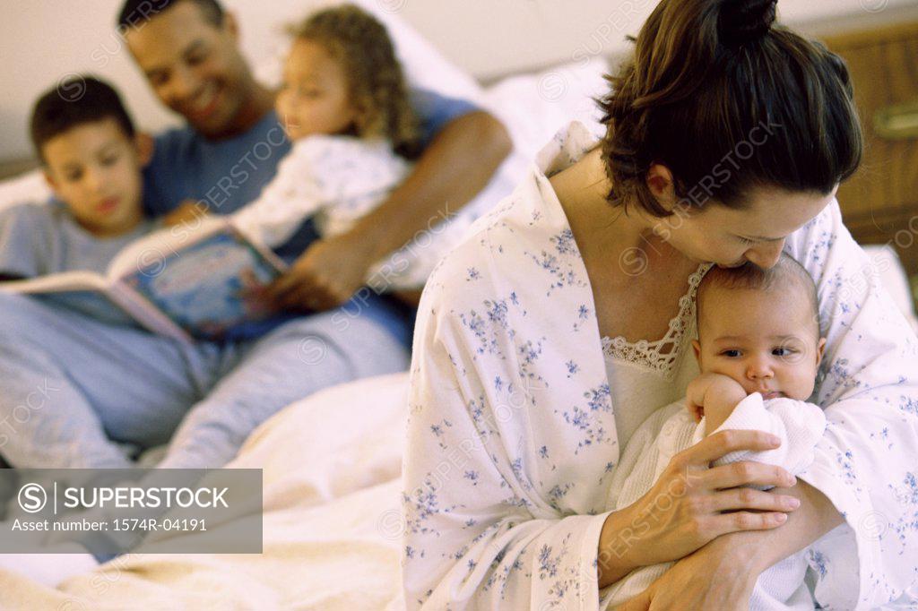 Stock Photo: 1574R-04191 Parents and their children sitting on a bed