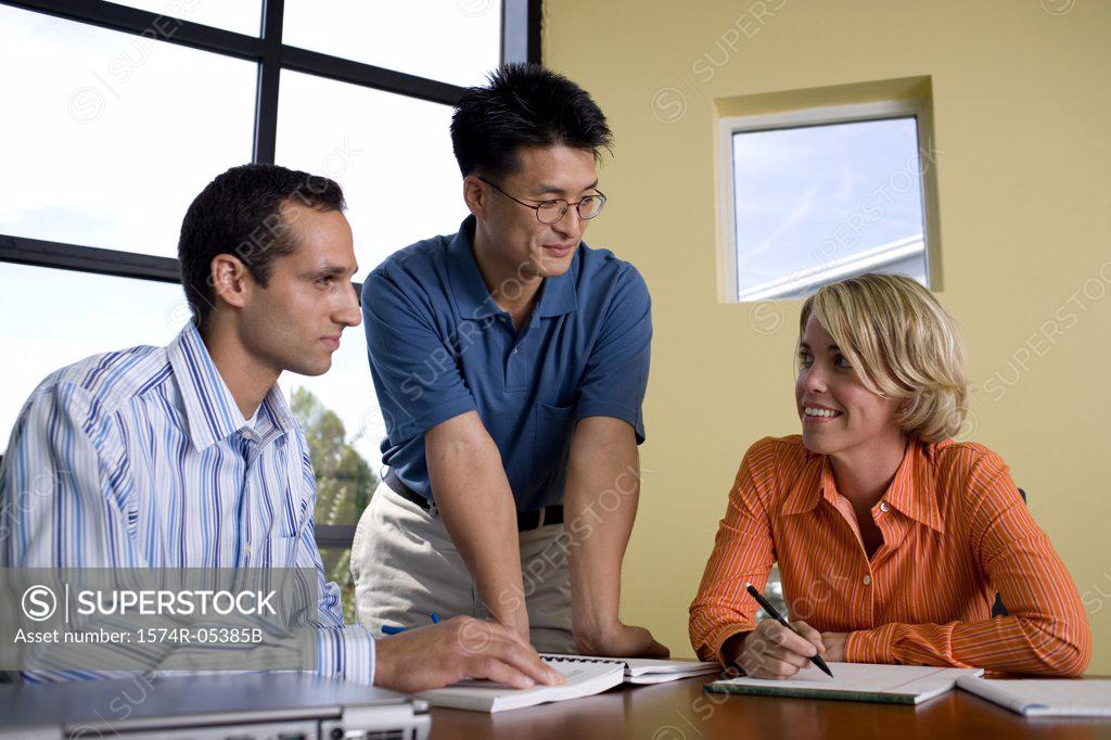 Stock Photo: 1574R-05385B Two businessmen and a businesswoman reading documents