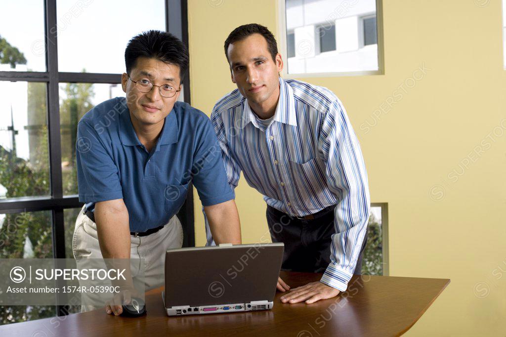 Stock Photo: 1574R-05390C Portrait of two businessmen standing in front of a laptop