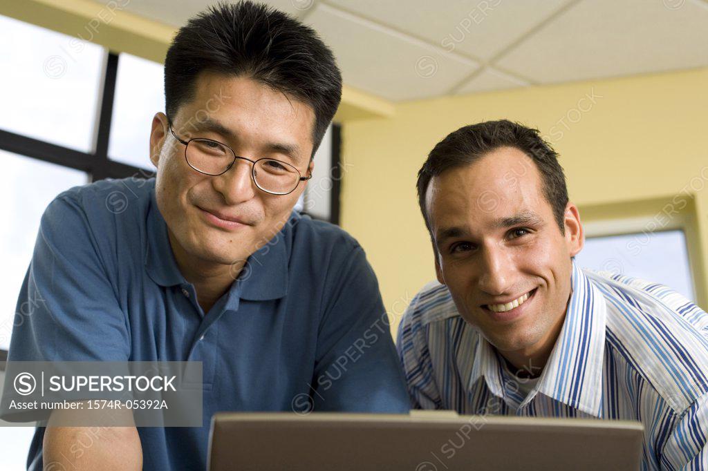 Stock Photo: 1574R-05392A Portrait of two businessmen standing in front of a laptop