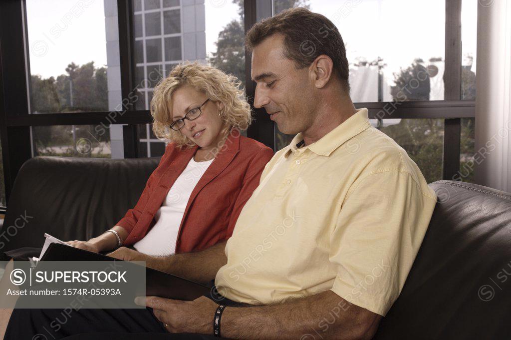 Stock Photo: 1574R-05393A Businessman and a businesswoman looking at documents in an office