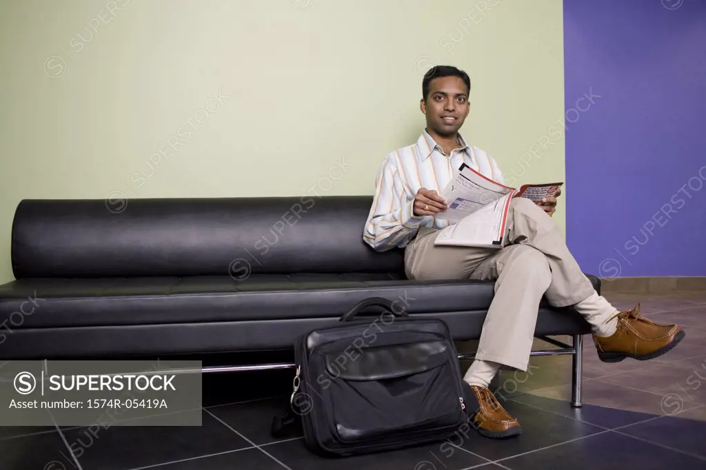 Portrait of a businessman sitting on a couch reading a magazine