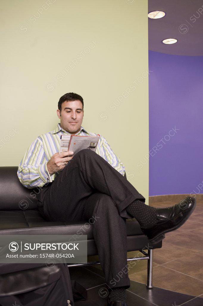 Stock Photo: 1574R-05420A Businessman sitting on a couch reading a magazine
