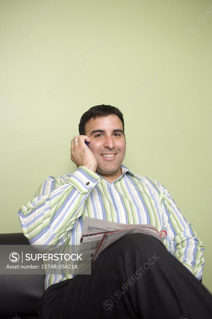 Stock Photo: 1574R-05421A Businessman sitting on a couch talking on a mobile phone in an office