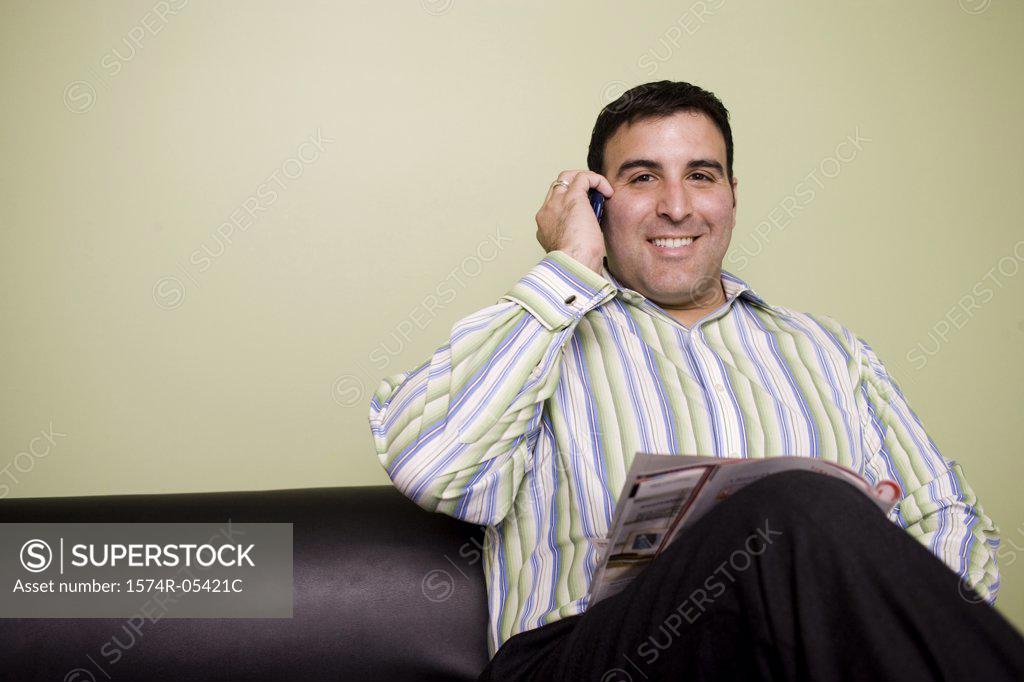 Stock Photo: 1574R-05421C Portrait of a businessman sitting on a couch talking on a mobile phone