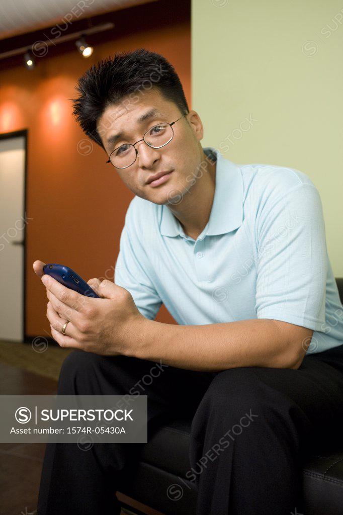 Stock Photo: 1574R-05430A Portrait of a businessman holding a mobile phone in an office