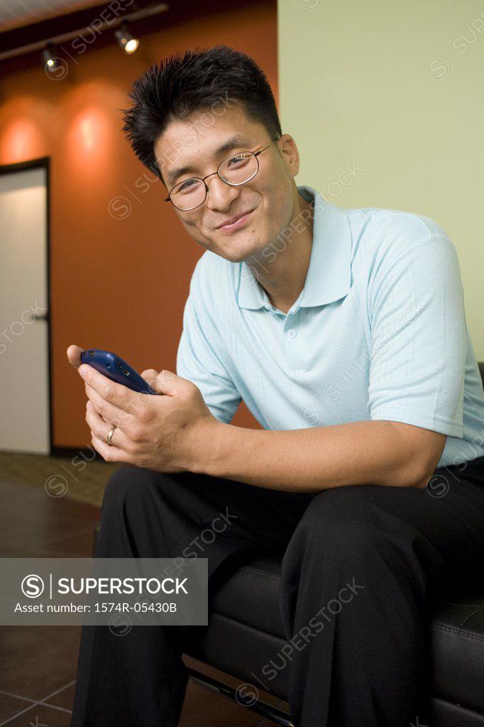 Stock Photo: 1574R-05430B Portrait of a businessman sitting in an office holding a mobile phone