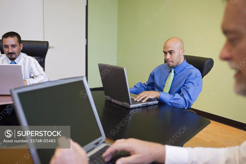 Stock Photo: 1574R-05483 Three businessmen working on laptops in a conference room