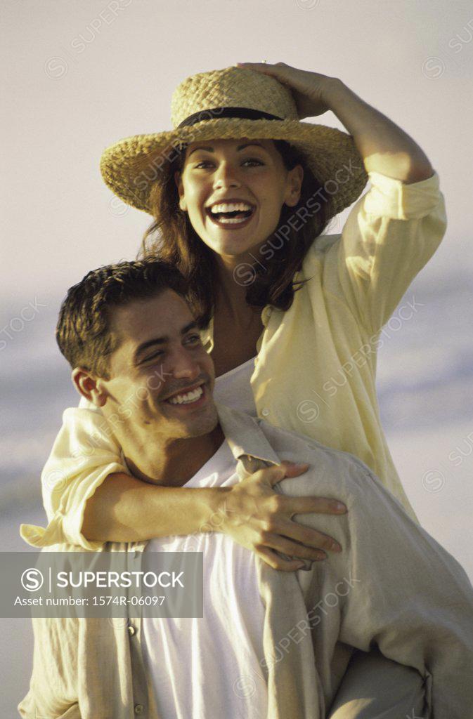 Stock Photo: 1574R-06097 Young woman riding piggyback on a young man on the beach