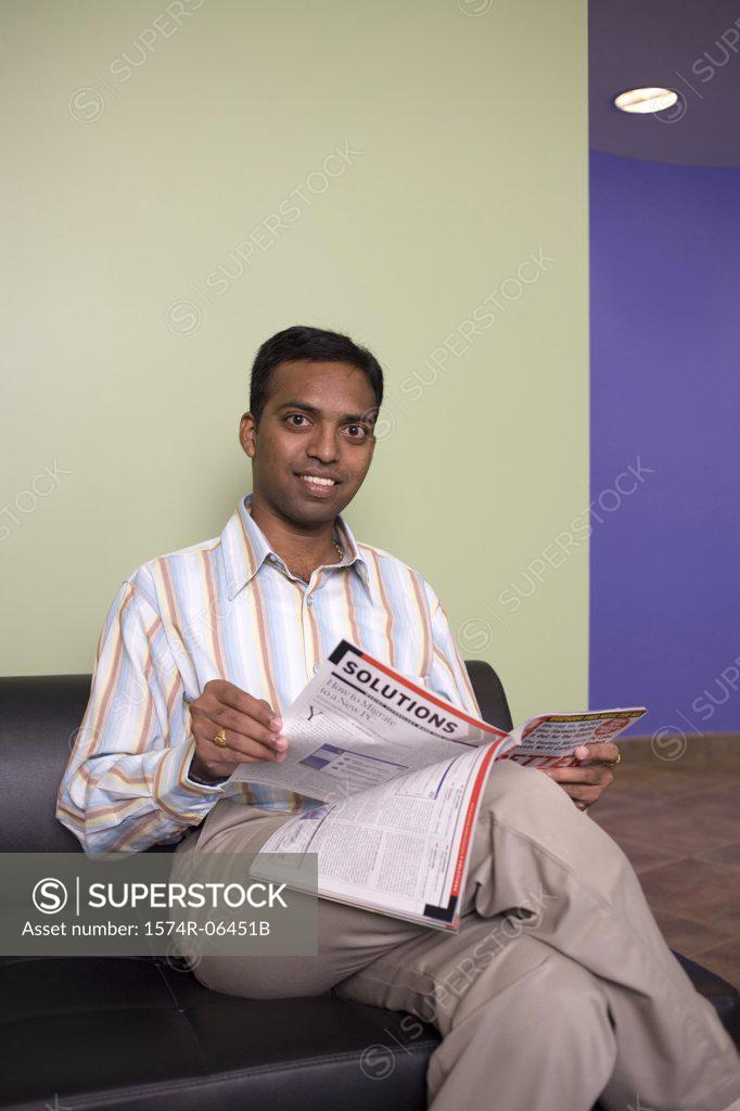 Stock Photo: 1574R-06451B Portrait of a businessman sitting on a couch reading a magazine in an office